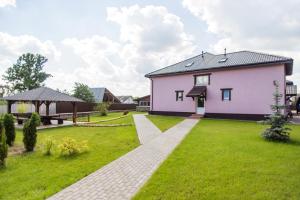 a house with a green yard with a pink house at Hotel Sofia in Polatsk