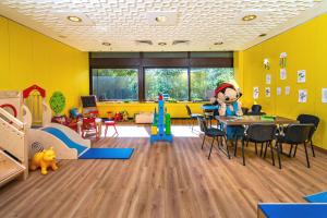 um quarto para crianças com paredes amarelas, uma mesa e cadeiras em AHORN Harz Hotel Braunlage em Braunlage