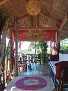 a porch with a table and chairs and a rug at OcamOcam Azur Inn in Busuanga