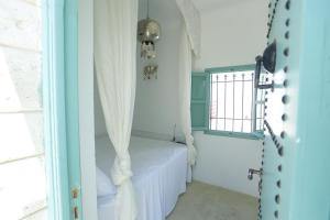 a room with a bed with a curtain and a window at Dar Hammamet Guest House & Hammam in Hammamet