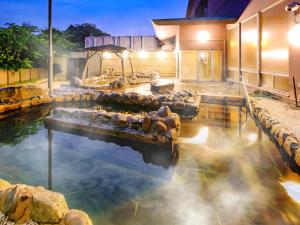 una piscina de agua con rocas en una casa en SPA HOTEL YUTTARIKAN en Satsumasendai