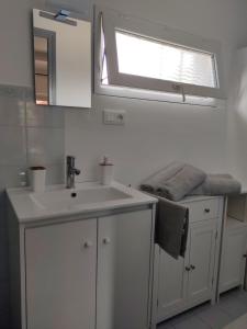 a white bathroom with a sink and a window at Charmante maisonnette à 2 min du Centre Ville in Casteljaloux