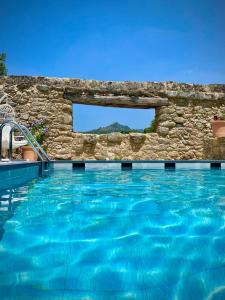 a swimming pool with a stone wall and blue water at Aqua Et Oleum in Villamiel