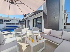 um pátio com mobiliário branco e um guarda-chuva em Luxury Villa by NRAS em Gran Alacant