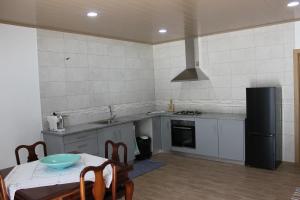 eine Küche mit einem Tisch und einem schwarzen Kühlschrank in der Unterkunft Casa do Avô Pedro 