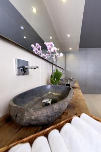 a bathroom with a large stone sink on a wooden counter at Ortunc Hotel - Cunda Island (Adult Only) in Ayvalık