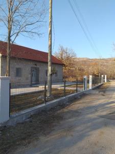 a fence in front of a house with a building at Vikendica Ćurić in Trebinje