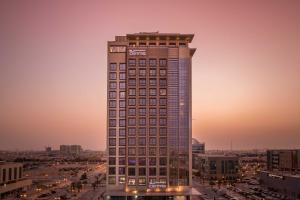 um edifício alto numa cidade ao pôr do sol em Centro Waha by Rotana em Riyadh