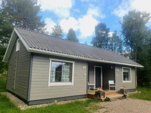 una pequeña casa gris con porche y ventana en Lucky Ranch cabin 3, en Pyhätunturi
