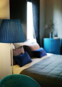 a bedroom with a bed and a blue lamp at Kaia Gallery Hotel Hoi An in Hoi An