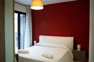 um quarto com uma cama branca e uma parede vermelha em La Dimora Dei Mori em Acitrezza