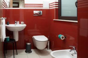 a red bathroom with a toilet and a sink at La Dimora Dei Mori in Acitrezza