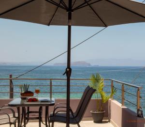 een terras met een tafel, stoelen en een parasol bij Tabak home Sea side apartment in Chania