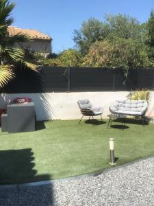 a yard with two chairs and a fence at Charmant Studio dans villa - parking - jardin in La Seyne-sur-Mer