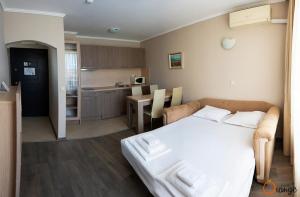 a bedroom with a white bed and a kitchen at Villa Orange in Sozopol