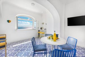 jadalnia ze stołem, krzesłami i telewizorem w obiekcie Casa Lou Positano w mieście Positano