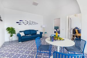salon z niebieską kanapą, stołem i krzesłami w obiekcie Casa Lou Positano w mieście Positano