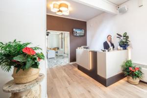 a woman standing at a reception desk in a lobby at Hotel Villa d'Este in Grado