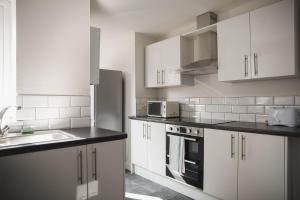 a kitchen with white cabinets and a sink at Green Park house in Leicester