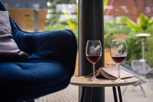 twee glazen wijn op een tafel naast een stoel bij A16 Design Panzió in Harkány