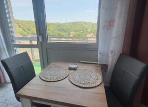 einen Holztisch mit zwei Stühlen und einem Fenster in der Unterkunft Hegyalja Apartman in Miskolc