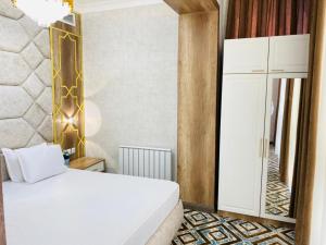 1 dormitorio con cama blanca y espejo en Khan Palace en Türkistan
