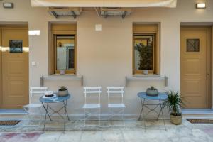 two tables and three stools in front of a building at Andy's & Hari's Elegant Town Studios in Zakynthos Town