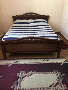 Una cama con una almohada a rayas encima de una alfombra en Friendly B&B, en Gyumri