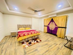 Holidazzle Serviced Apartments Bahria Town في روالبندي: غرفة نوم بسرير وبطانية ارجوانية وصفراء