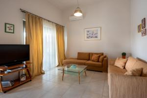 a living room with a couch and a tv at Blue Wave Villa - road view in Gennadi