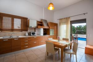 a kitchen with a wooden table and chairs and a dining room at Blue Wave Villa - road view in Gennadi