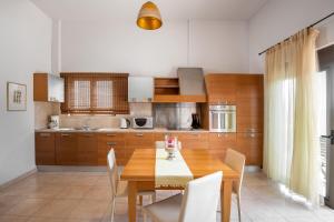 a kitchen with a wooden dining table and chairs at Blue Wave Villa - road view in Gennadi