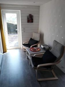 a room with two chairs and a table and a door at Studio Au jardin fleuri in Verviers
