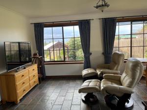 a living room with two chairs and a couch and windows at Bicheno getaway for two in Bicheno