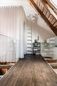 Habitación en el ático con suelo de madera y cortinas blancas en MAISON de la Bonne Vie, en Thérondels