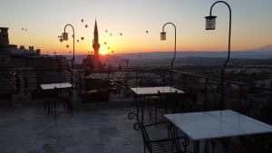 um pátio com mesas e cadeiras e o pôr-do-sol em Kappadoks Cave Hotel em Üçhisar