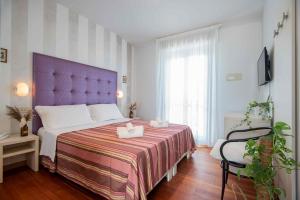 a bedroom with a large bed with a purple headboard at Hotel Baby in Milano Marittima