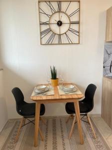 a wooden table with two chairs and a clock on the wall at Ferienwohnung AllgäuSchatz Kempten in Kempten