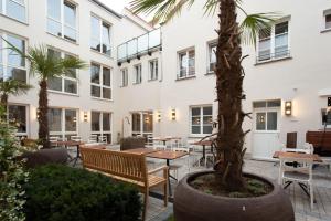 un patio con mesas, sillas y una palmera en Hotel Tuchhaus, en Volkach