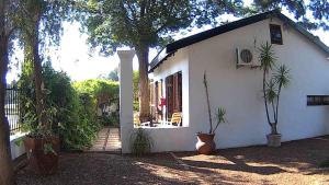 a small white house with plants in front of it at Kuru-Kuru Guesthouse in Kuruman