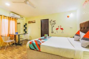 1 dormitorio con 1 cama y 1 mesa con sillas en FabExpress Victoria With Pool, Baga Beach en Baga