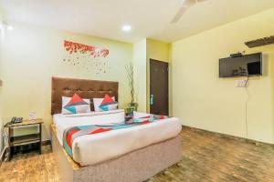 een slaapkamer met een groot bed en een flatscreen-tv bij FabExpress Victoria With Pool, Baga Beach in Baga