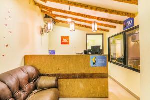 a waiting room with a leather couch in front of a counter at FabExpress Victoria With Pool, Baga Beach in Baga