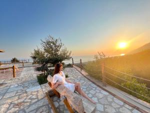 a woman sitting on a bench watching the sunset at Rahoni Park & Suites in Dhërmi
