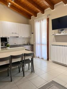 Una cocina con mesa y sillas y un televisor. en Appartamento Corina, en Sirmione