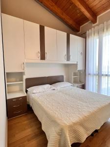a bedroom with a bed and white cabinets and a window at Appartamento Corina in Sirmione