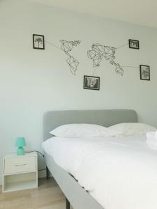 - une chambre dotée d'un lit blanc avec des photos sur le mur dans l'établissement Mon appart Bougnat, à Clermont-Ferrand
