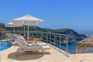 a woman and a dog sitting on a chair under an umbrella at Petani Bay Hotel - Adults Only in Vóvikes