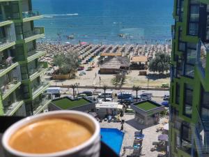 una taza de café con vistas a la playa en SUNSHINE PLACE ApartHotel Pool & Spa Mamaia Nord en Mamaia Nord – Năvodari