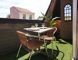 - une table avec 2 chaises et des verres à vin sur la terrasse dans l'établissement Mon appart Bougnat, à Clermont-Ferrand